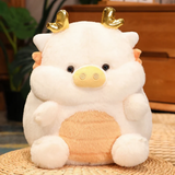 White pig-dragon plush cushion with golden horns on a wicker mat, showing its cream belly in a cozy indoor setting.
