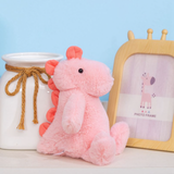 Pink dinosaur plush sitting beside a picture frame and a glass jar