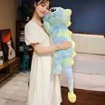 Woman in a white dress hugging a tall blue and green rainbow dinosaur plush