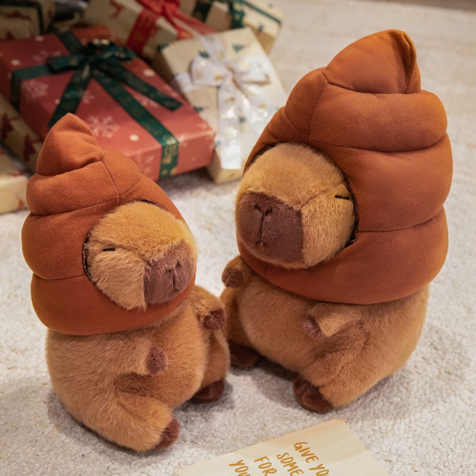 Two capybara plushies with brown swirl hats sitting on a rug