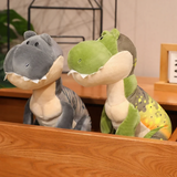 Green and gray T-Rex dinosaur plush toys sitting on a wooden surface.