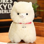 White alpaca plush with a red bell collar sitting on a wooden table