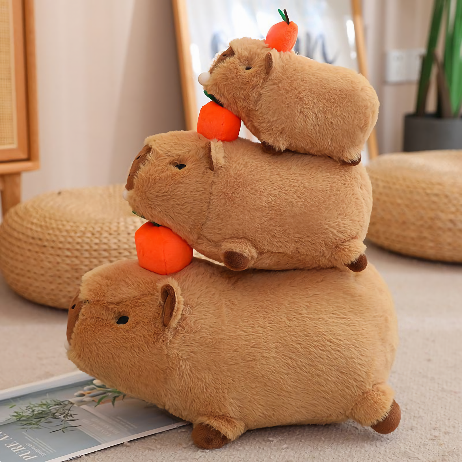 Three lying capybara plushies with oranges stacked on a woven stool