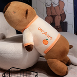 Capybara plush pillow with an orange trim shirt propped against a chair