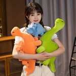 Woman holding green Brontosaurus, orange Stegosaurus, and blue Triceratops plush dinosaurs.