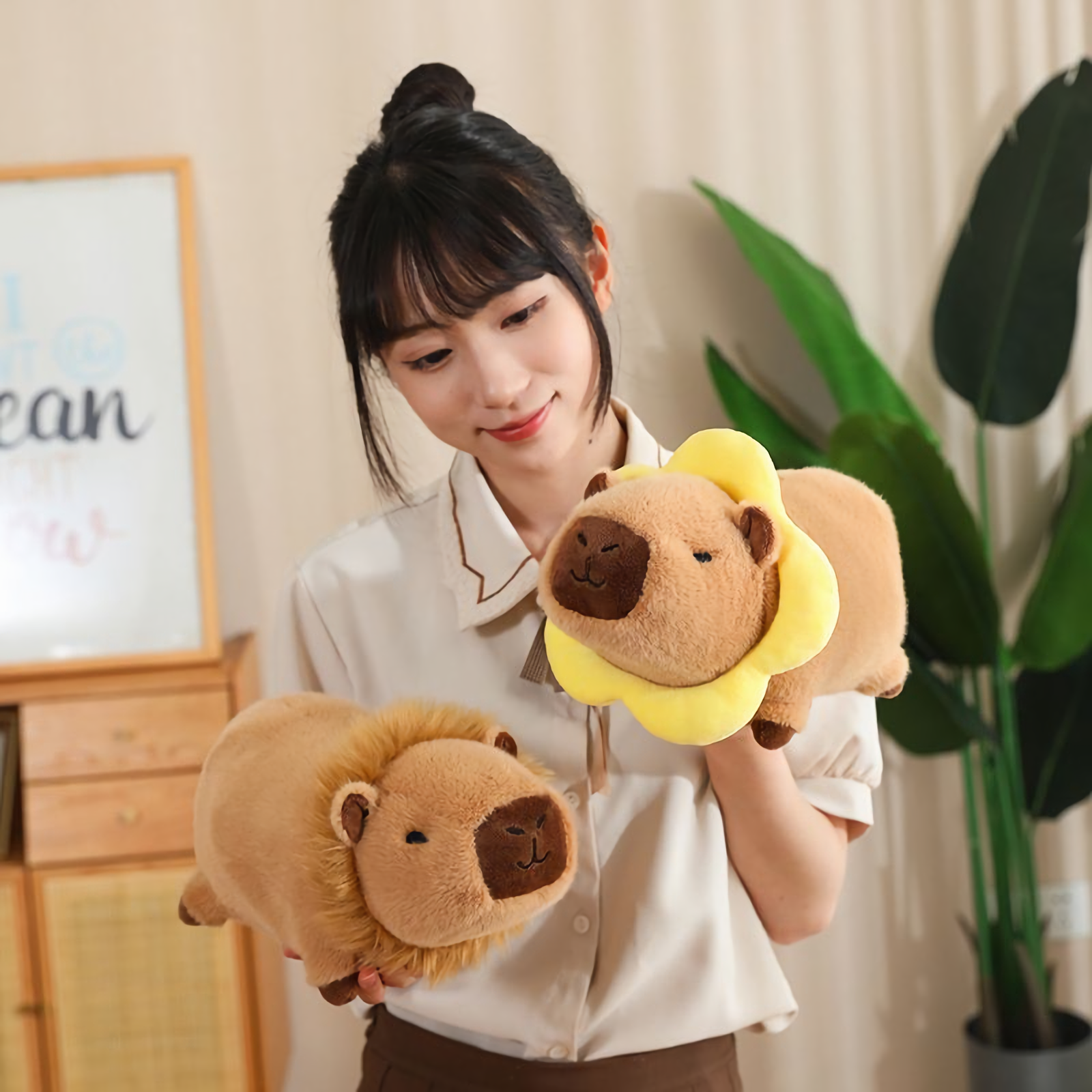 Woman holding a yellow flower capybara plush and a lion capybara plush