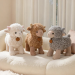 White, brown and gray curly lamb plushies standing on a cream sofa