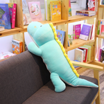 Long blue dinosaur plush body pillow leaning against a dark sofa in a bright room