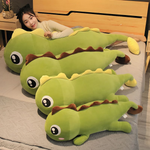 Woman lying on bed with green dinosaur plush pillows with brown spikes, varying sizes, next to her.