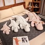 Four dragon plush body pillows in pink and white on a bed, showcasing different sizes.