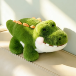 Large green alligator plush lying on a sofa with orange spikes on its back