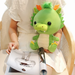 Woman seated with green dragon plush on her lap, magazine in hand.