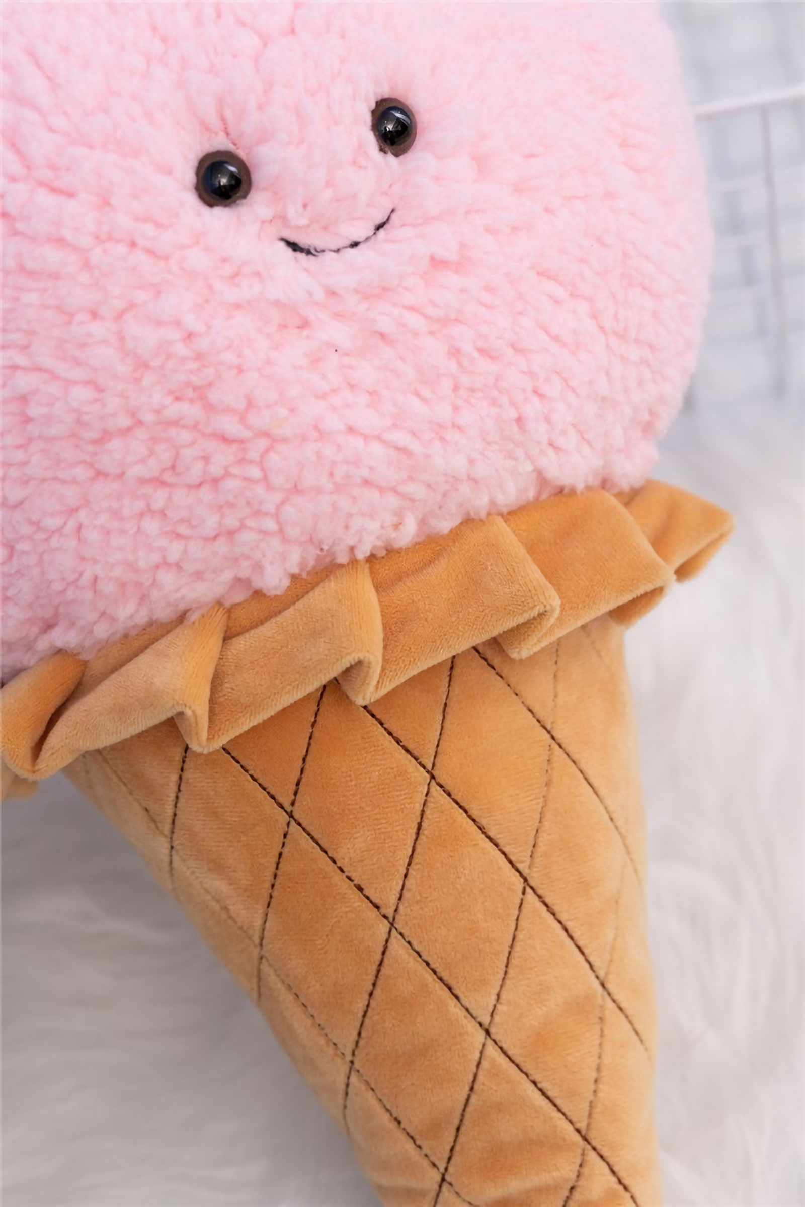 Close-up of a pink ice cream cone plush pillow with a quilted waffle cone