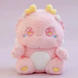 Pink fluffy baby dragon plush with sparkly star eyes and golden horns, sitting on a pink background.