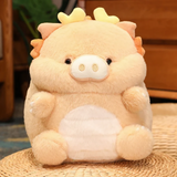 Peach pig-dragon plush with cream belly on woven mat, showing its round fluffy body and tiny horns.