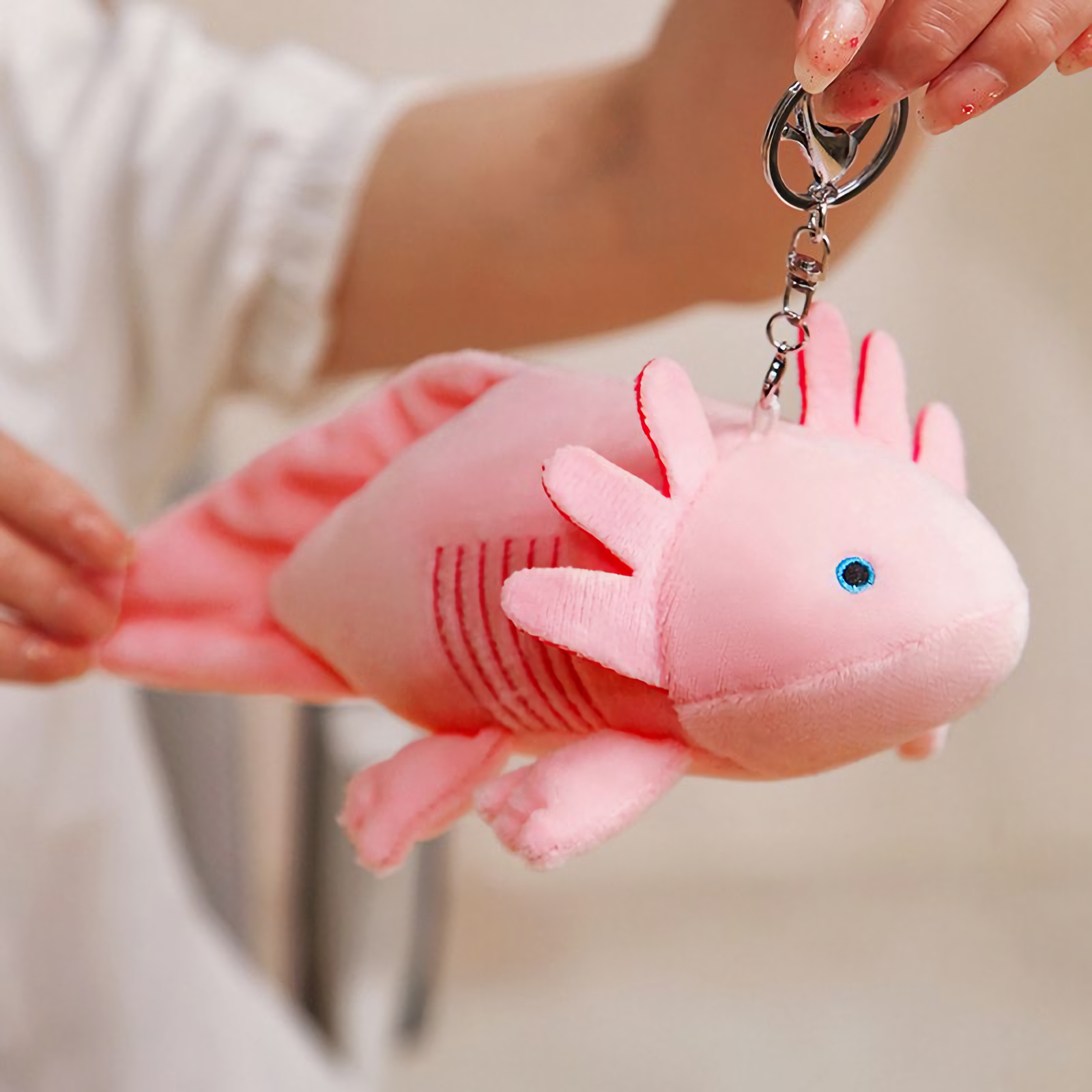 Woman holding a pink axolotl plush by a clip ring