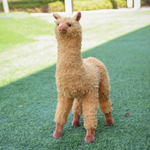 Brown standing alpaca plush with a long neck and soft hooves on grass