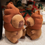 Two capybara plushies with brown swirl hats in front of gift boxes