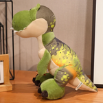 Green T-Rex dinosaur plush with a yellow-orange belly sitting on a wooden surface.