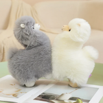 Gray and white alpaca plushies standing side by side on a table