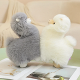 Gray and white alpaca plushies standing side by side on a table