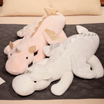 Pink dragon plush and white dragon plush lying side by side on a gray bed
