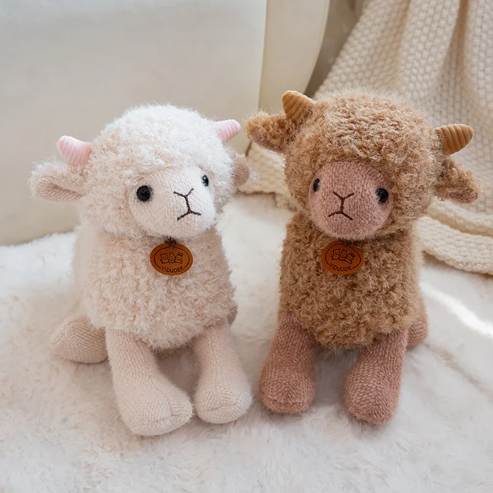 White and brown curly lamb plushies standing on a fluffy white rug