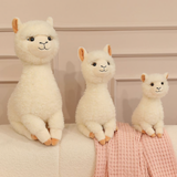Three cream white alpaca plushies in different sizes on a sofa