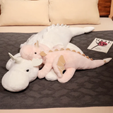 Pink and white dragon plush body pillows on a bed with a magazine nearby.
