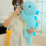 Woman holding a blue dinosaur plush with heart-shaped spikes, taking a photo with a smartphone.