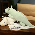 Mint green and white dragon plush pillows on a wooden table, overlapping each other.