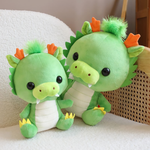 Two green dragon plush toys with orange horns on a sofa.