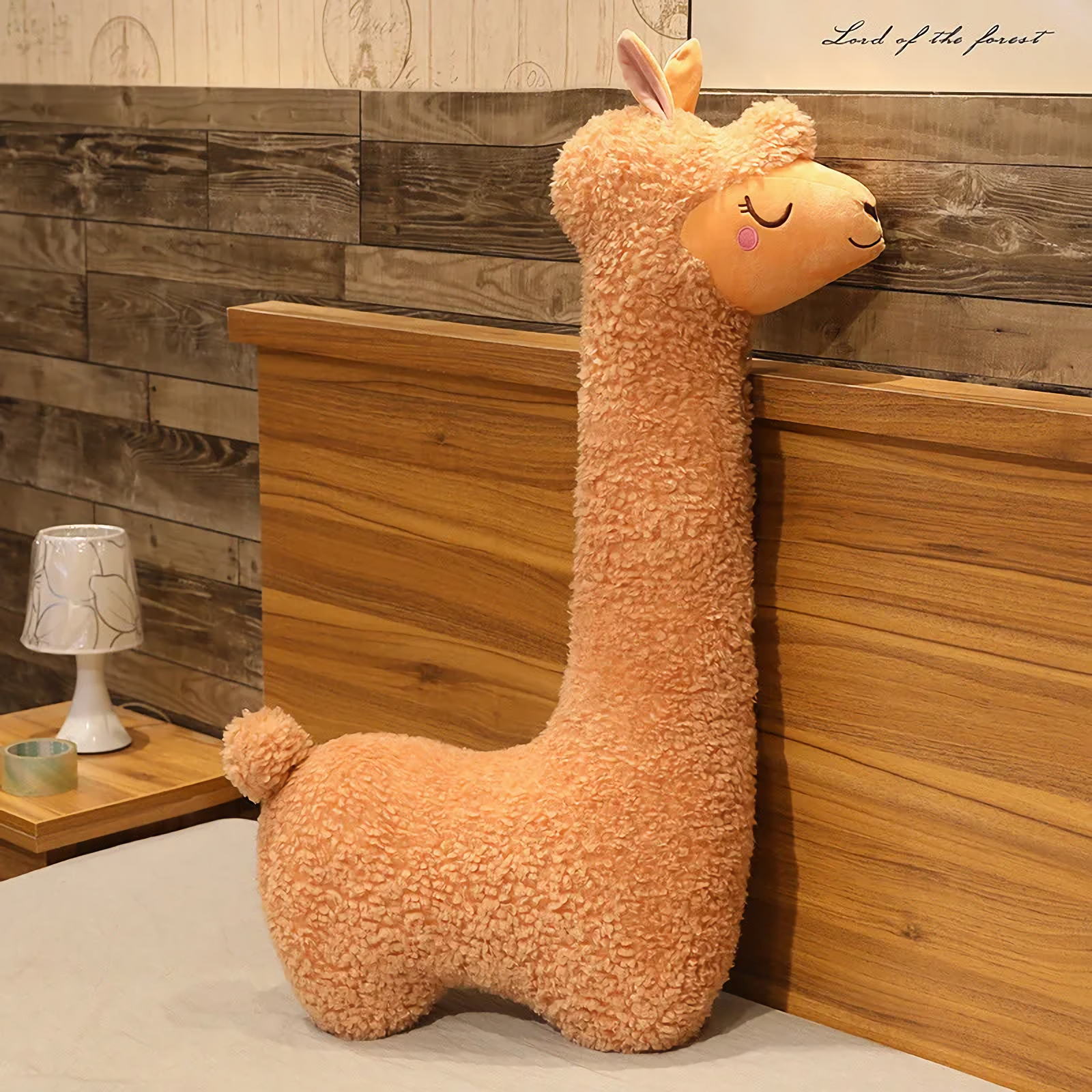 Brown long alpaca plush pillow standing against a wooden headboard