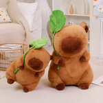 Two lotus leaf capybara plushies of different sizes on a rug