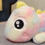 Close-up of a rainbow dinosaur plush face with a large sparkly eye and a yellow horn