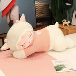 White sleeping sheep plush pillow with a pink knit sweater lying on a pink blanket