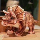Brown Triceratops dinosaur plush with detailed frill and horns stands on a wooden surface.
