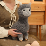 Woman holding a gray fluffy alpaca plush in her lap