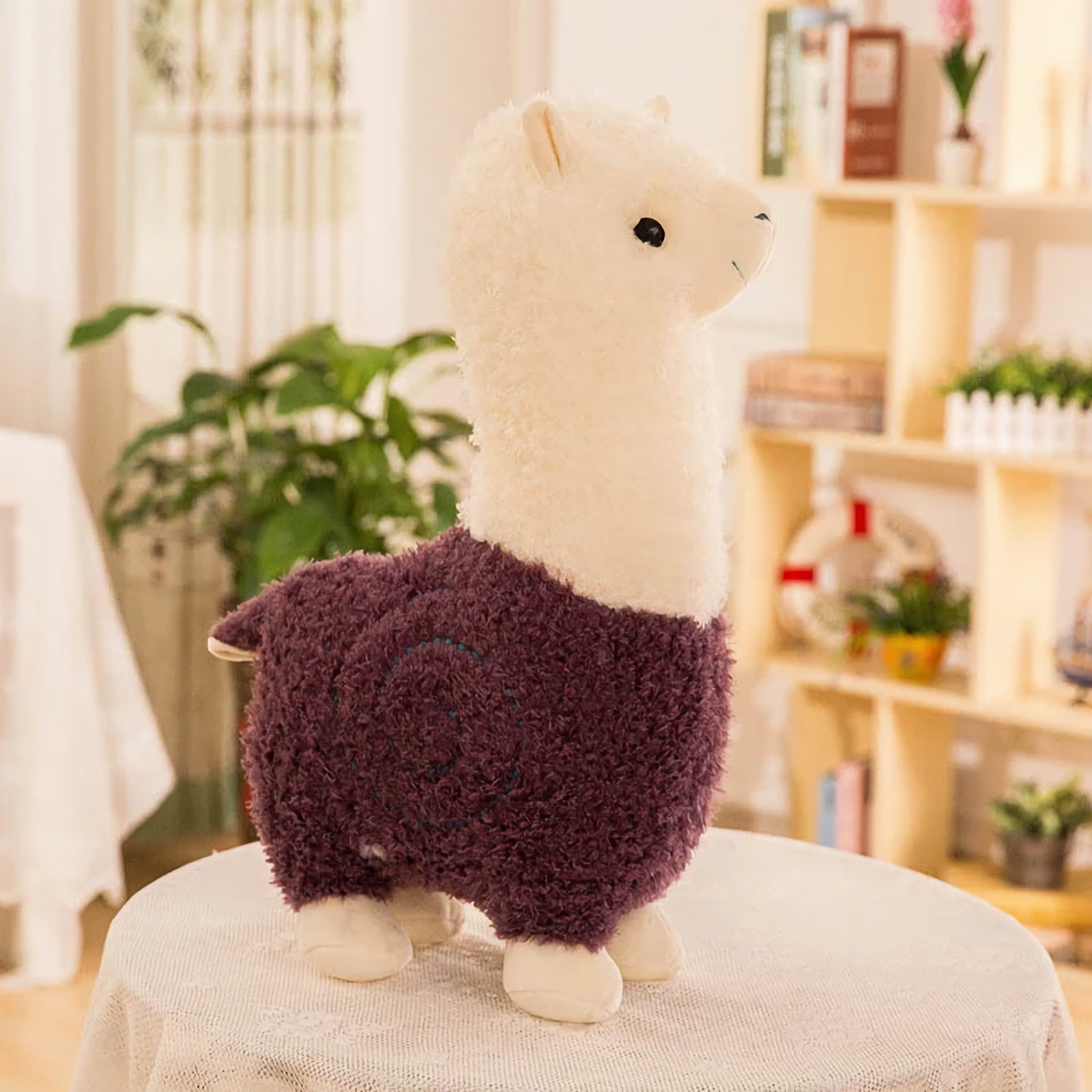 Purple body alpaca plush with a white head and a stitched swirl on a table