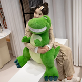 A woman hugging a large green T-Rex dinosaur plush with a pale green belly and dark teal claws.