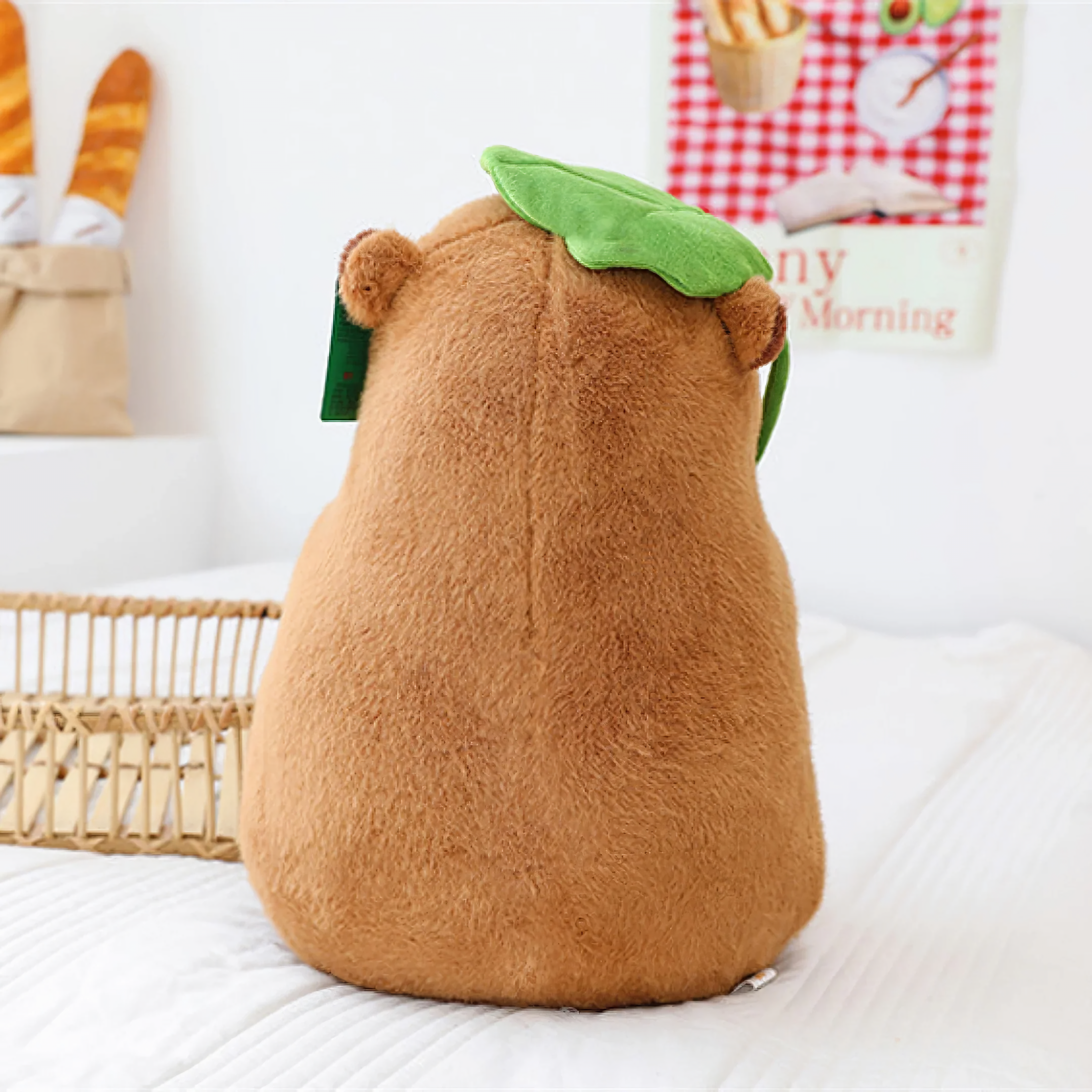 Back view of a capybara plush with a green lotus leaf on its head