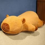 Lying capybara plush pillow with a sleepy face on a gray sofa