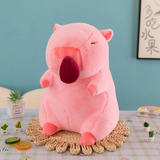 Pink sitting capybara plush with an open mouth on a woven mat