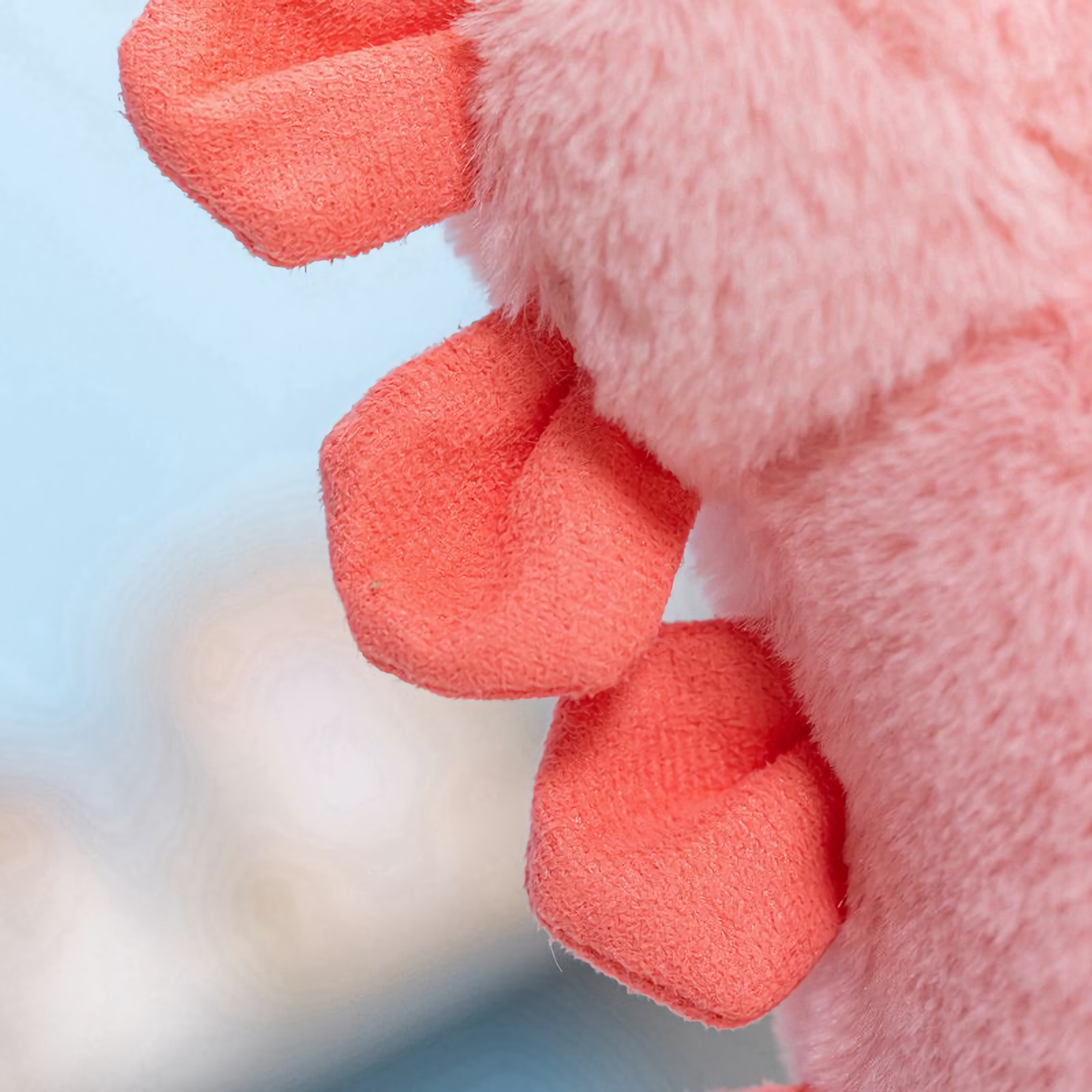 Close-up of the coral red spikes on a pink dinosaur plush