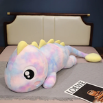 Rainbow Purple dinosaur plush body pillow in pink and blue tie dye with big eyes on a bed