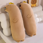 Two long tan capybara body pillows with gold crowns leaning on a fluffy headboard