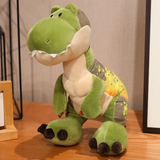 Green T-Rex dinosaur plush with a cream belly and dark feet sits on a wooden table.