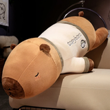 Large capybara plush pillow with a cream shirt lying on a beige sofa
