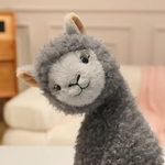 Close-up of a gray fluffy alpaca plush with a light gray face and tan ears