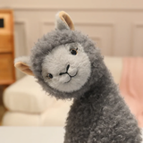 Close-up of a gray fluffy alpaca plush with a light gray face and tan ears